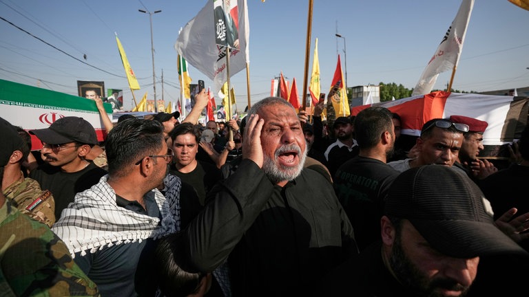 Trauernde tragen Särge, die mit der iranischen Fahne (l) und der irakischen Fahne (r) bedeckt sind, während einer Beerdigung für Kämpfer der «Popular Mobilization Forces», die bei Luftangriffen auf Stützpunkte ums Leben gekommen sind.