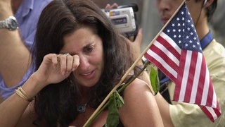 Eine Frau wischt sich die Tränen weg an einer provisorischen Gedenkstätte, die in New York nach den verheerenden Terroranschlägen vom 11. September 2001 eingerichtet wurde.