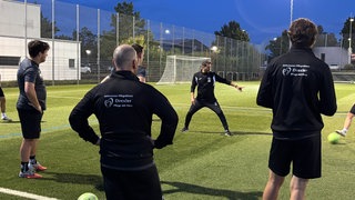 Auf einem Fußballfeld stehen mehrere Spieler in Trikots