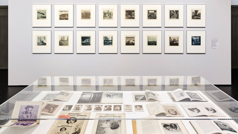 Im Hintergrund: Motive aus der Mappe „Ansichten aus den Stickstoffwerken der I.G. Farbenindustrie Aktiengesellschaft“