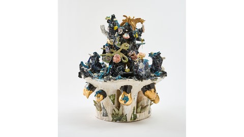 Die 90 Zentimeter große Skulptur von Nora Arrieta heißt "Toteninsel" und zeigt viele kleine Objekte, wie Handys, Köpfe oder Kinderspielzeug, die mit viel blauer Glasur verbunden sind.