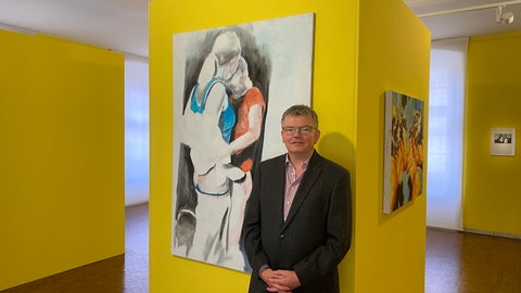 Mann vor gelber Wand mit Kunst