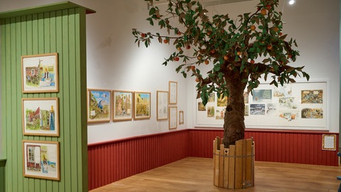 Blick in die Ausstellung zu Pettersson und Findus in Karlsruhe, im Zentrum ein Apfelbaum