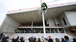 Der Richtkranz beim Richtfest für den Neubau des Museums Berlin Modern am Kulturforum in Berlin-Tiergarten von einem Kran hochgezogen.