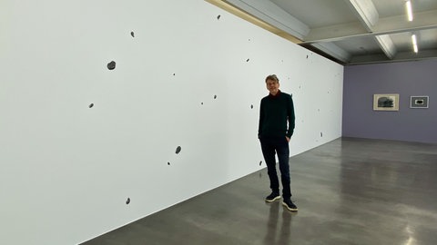 Kurator Holger Kube Ventura vor einem Kunstwerk von Marco Gastini
