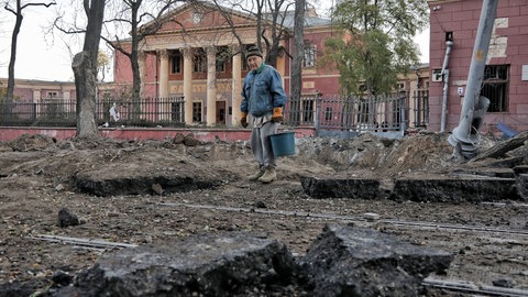 Nach einem nächtlichen russischen Raketenangriff steht ein älterer Mann vor dem Krater einer Rakete auf der Straße vor dem Nationalen Kunstmuseum. 