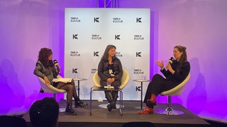 SWR Kultur Messe-Talk auf der ART Karlsruhe: Die Künstlerinnen Tamiko Thiel und Gretta Louw auf der Bühne mit Moderatorin Helen Roth