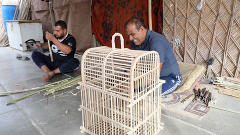 Kunsthandwerker fertigen einen Vogelkäfig aus Dattelpalmenblättern