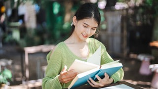 Junge Frau mit Buch auf dem Schoß, Titebild Lesenswert Magazin am 31.08.2025