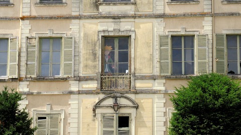 Im Fenster in der Mitte des Gebäudes sieht man eine Nachbildung vom kleinen Prinz. Saint-Exupéry verbrachte einen Großteil seiner Kindheit in dem Schloss Saint-Maurice-de-Rémens aus dem 18. Jahrhundert. 