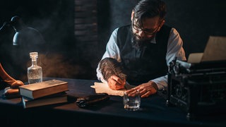 Mann schreibt Brief mit Feder, düster, altertümlich