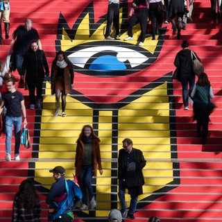 Zahlreiche Besucher gehen die Treppe mit dem Logo der Leipziger Buchmesse hinab. 