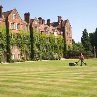 Mann mäht Rasen im Innenhof des Selwyn College, Universität Cambridge, England