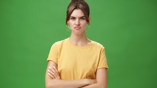 Eine unzufriedene Frau runzelt die Stirn und schürzt die Lippen