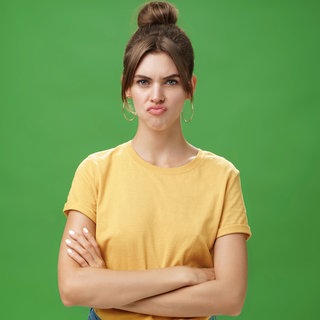 Eine unzufriedene Frau runzelt die Stirn und schürzt die Lippen