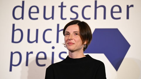 Die Schweizer Autorin Dorothee Elmiger vor dem Logo des Deutschen Buchpreises