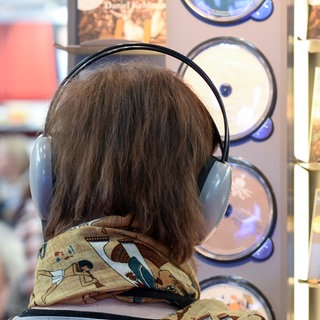 Ein Frau mit Kopfhörern hört Hörbücher auf der Leipziger Buchmesse. 