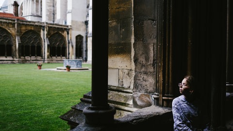 Junges Mädchen schaut durch ein altes Kirchenfenster in Oxford, England.