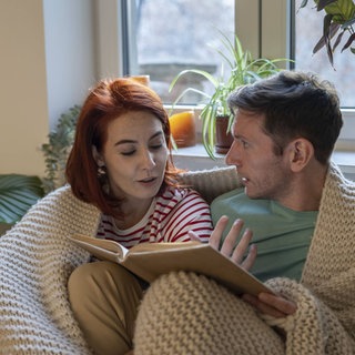 Paar mit Buch auf dem Sofa, Lemag 09.11.2025