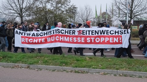 Linke Aktivisten gehen mit Transparenten während der Buchmesse "Seitenwechsel" zur Messe