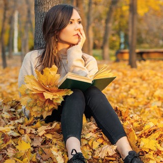 Junge Frau mit Buch im herbstlichen Wald