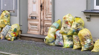 Ein Berg aus gelben Müllsäcken vor einer Eingangstür
