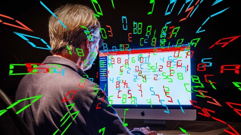 Mann arbeitet nachts am Computer und bedient ChatGPT, während bunte Zahlen aus dem Computer kommen