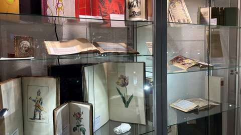 Vitrine zeigt hochpreisige Ausgaben mit altkolorierten Blumenkupferstichen