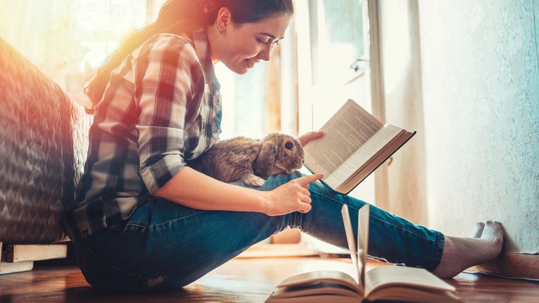 Junge Frau sitzend mit Kaninchen und Buch, lesenswert Magazin 29.03.2026