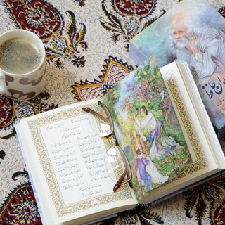 Divan-e-Hafez Buch, Gedichte des Iranischen Poeten Hafez geöffnet auf traditionellem Tischtuch mit Kaffeetasse