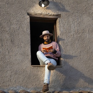 Mann mit Buch im Fensterrahmen sitzend, lesenswert Magazin 31.05.2026