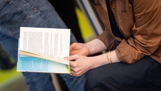 Frauenhände halten ein Buch, lesende Haltung