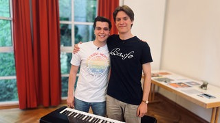 Die Brüder Cornelius und Quintus Appelmann stehen Arm in Arm am Keyboard.