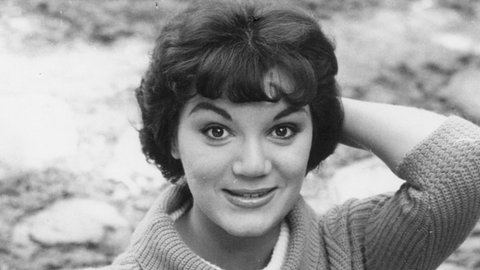 Sängerin Connie Francis in schwarz-weiß. Sie posiert mit einem Schirm und lächelt in die Kamera.