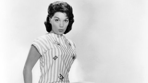 Die amerikanische Schlagersängerin Connie Francis posiert in schwarz-weiß auf einem Stuhl und spitzt die Lippen.