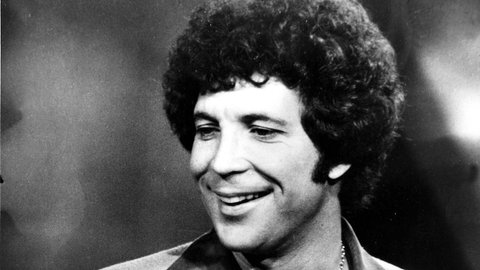 Schwarz-weiß Bild von Tom Jones mit einem Mikrofon in der Hand im Jahr 1976