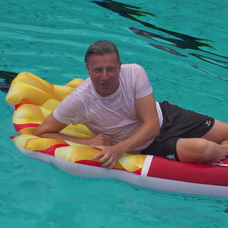 Jörg Augenstein liegt auf einer Luftmatratze in einem Pool
