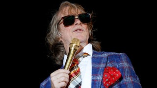 Helge Schneider - typisch mit großere Sonnenbrille und zu großgeratenem Anzug im Karomuster