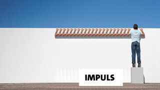 Ein Mann schaut über eine Mauer 