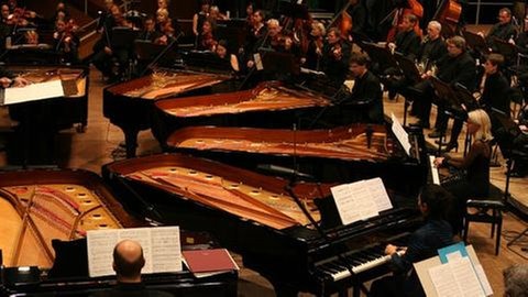 Musiker des SWR Sinfonieorchesters Baden-Baden und Freiburg sowie Solisten an sechs Flügeln bei einem Konzert