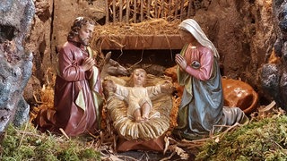 Das Jesus-Kind in der Krippe zusammen mit Maria und Josef