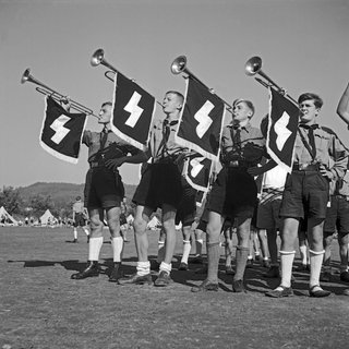 Vier Trompeter des Jungvolk-Musikzuges blasen zum Antreten im Hitlerjugend-Lager.