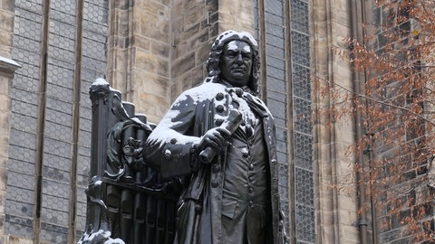 Schneebedecktes Standbild Johann Sebastian Bachs vor der Thomaskirche in Leipzig.