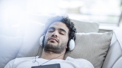 Ein Mann schläft, er hört dabei mit Kopfhörern Musik