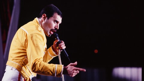Queen-Frontmann Freddie Mercury beim Live Aid Konzert von Queen in seiner ikonischen, gelben Jacke