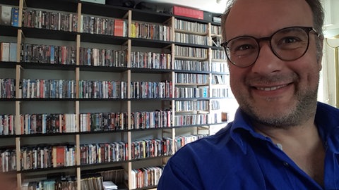 Kabarettist René Sydow vor seiner Medien-Sammlung