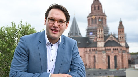 Gabriel Venzago, Chefdirigent und Generalmusikdirektor des Philharmonischen Staatsorchesters Mainz, steht am Rande einer Pressekonferenz auf der Terrasse des Staatstheaters in unmittelbarer Nachbarschaft des Doms.