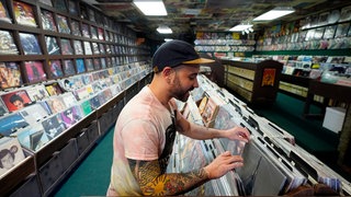 Ein Mann sucht in einem Plattenladen nach einer Vinyl-LP