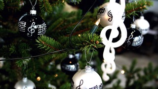 Weihnachtskugeln mit Noten hängen an einem Weihnachtsbaum