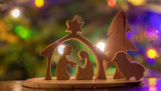 Holzkrippe mit Lichtern im Hintergrund